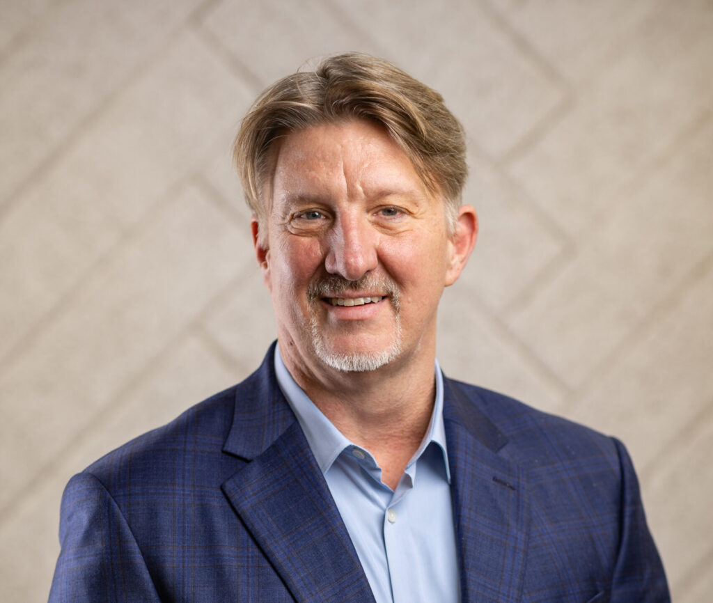 Portrait of a man in a blue suit jacket and light blue shirt smiling